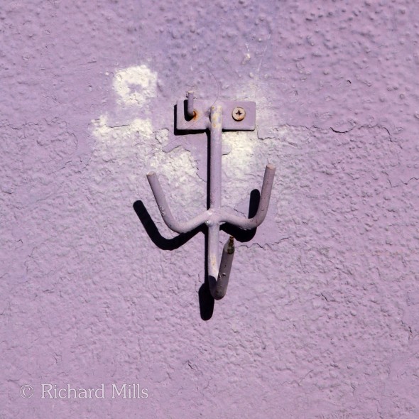 Mauve painted wall with a three pronged hook, on the island of Burano. A train trip to Venice via London, Paris and Munich in October 2014.